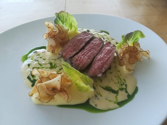 Ein Steak auf einem weißen Teller mit Salat serviert