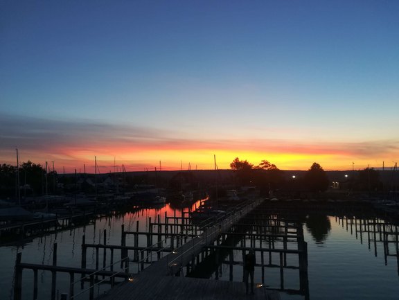 Sonnenuntergang am Yachthafen: Ruhige Gewässer, leuchtende Farben und Boote, die sich im Abendlicht spiegeln.